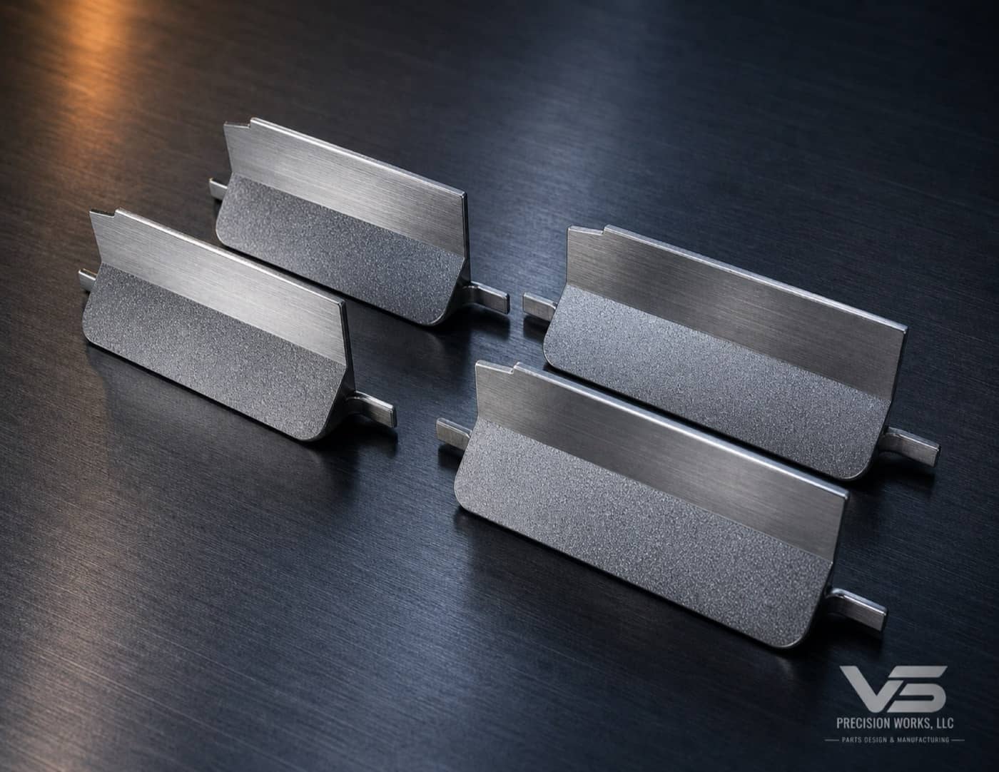 Four milled stainless catheter gripper parts with brushed faces